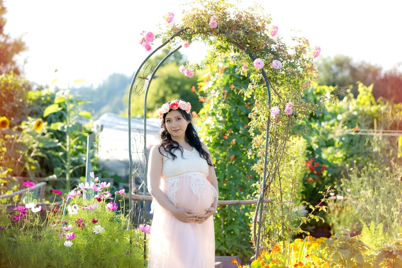 A picture of a woman standing in front of a flower arch