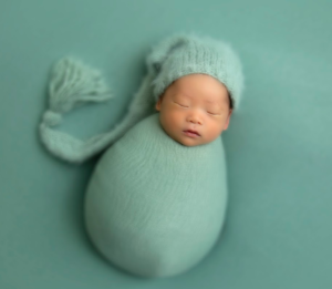 A baby is sleeping while wearing a wrap and hat set