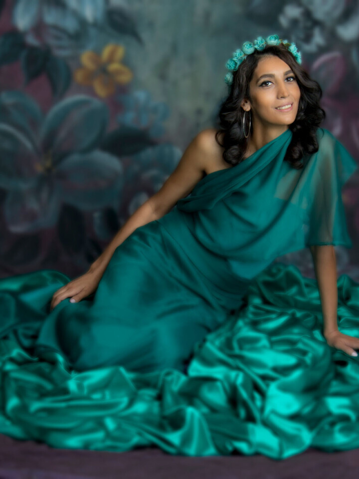 Artin Headshot & Portrait Photography Vancouver are A woman in a green gown sitting against a purple background