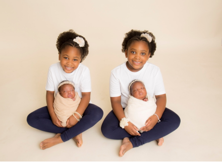 Include Siblings in Baby's Photoshoot - Two sisters holding their newborn twin sisters