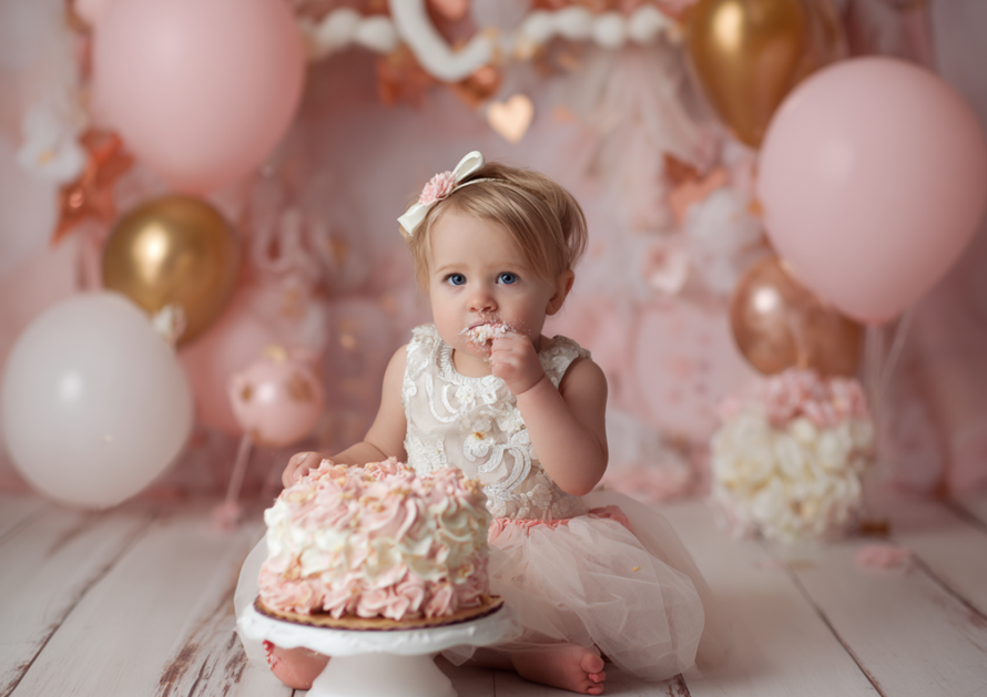 Toddler girl eating her cake at a pink themed cake smash photo session